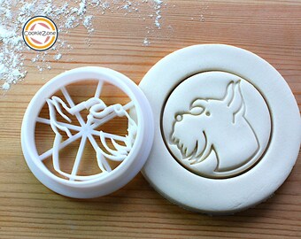 May include: White plastic cookie cutter in the shape of a dog's head. The cutter is shown next to a piece of dough that has been pressed with the cutter.