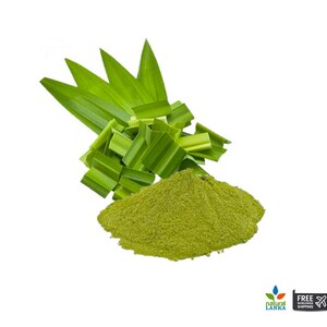 May include: A pile of fine, vibrant green pandan leaf powder positioned in front of a cluster of fresh, elongated, bright green pandan leaves. The leaves are pointed and arranged in a fan-like formation behind the textured powder mound.