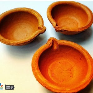 May include: Three terracotta clay diya oil lamps, traditional Indian oil lamps used for religious ceremonies and festivals.