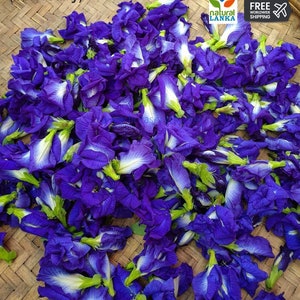 May include: A close-up image of a pile of dried blue butterfly pea flowers. The flowers are arranged on a woven bamboo mat. The text "natural lanka" and "free worldwide shipping" is visible in the upper right corner of the image.