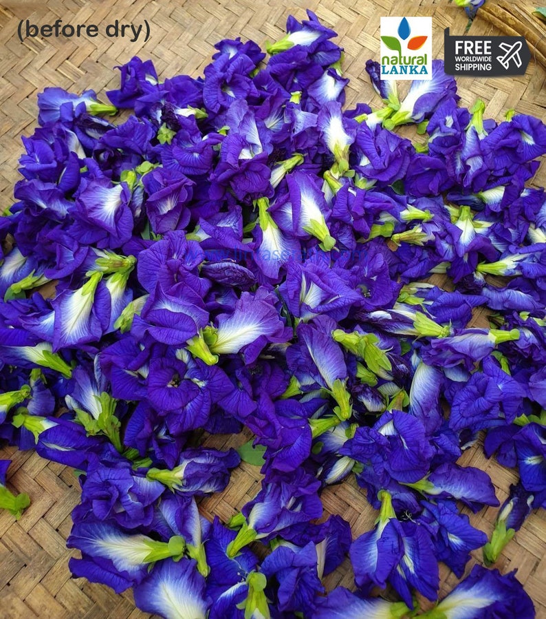 May include: A close-up image of a pile of dried blue butterfly pea flowers. The flowers are arranged on a woven bamboo mat. The text "natural lanka" and "free worldwide shipping" is visible in the upper right corner of the image.