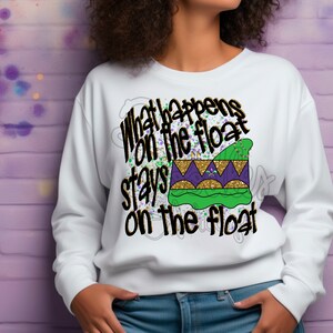 May include: White sweatshirt with a black and gold graphic that says "What happens on the float stays on the float". The graphic also includes a purple and gold Mardi Gras crown.