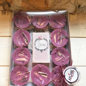 May include: A box of 10 pink wax melts with wood pieces embedded in them. The box has a label that says "Christmas".
