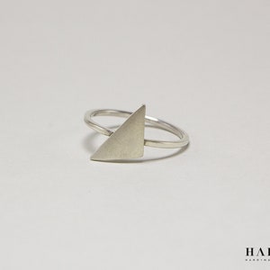 Pode incluir: Um anel de prata com um design de forma triangular. O anel é simples e moderno.