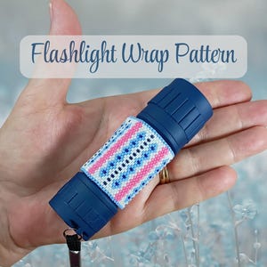 May include: A dark blue flashlight featuring a decorative beaded wrap pattern in white, pink, and light blue. The wrap displays a geometric design with a central vertical row of dark blue beads. The text Flashlight Wrap Pattern is visible.