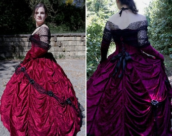 May include: A full-length, burgundy velvet ball gown with a black lace overlay and a black ribbon sash. The gown has a fitted bodice and a full skirt with ruffles.
