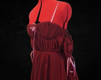 May include: A maroon dress with a sweetheart neckline and puffed sleeves. The dress has pink ribbon accents and a gathered skirt.