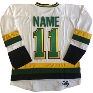 May include: White hockey jersey with green and gold stripes. The back of the jersey has the number "11" in gold with a green outline and the word "NAME" above it. The bottom of the jersey has a black stripe with the word "Tally" in cursive.