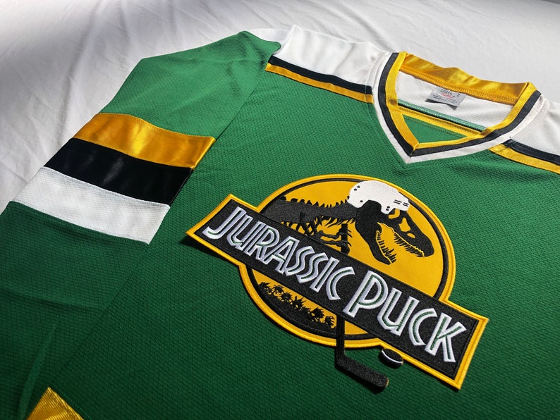 May include: Green and yellow hockey jersey with a dinosaur graphic and the text "Jurassic Puck".