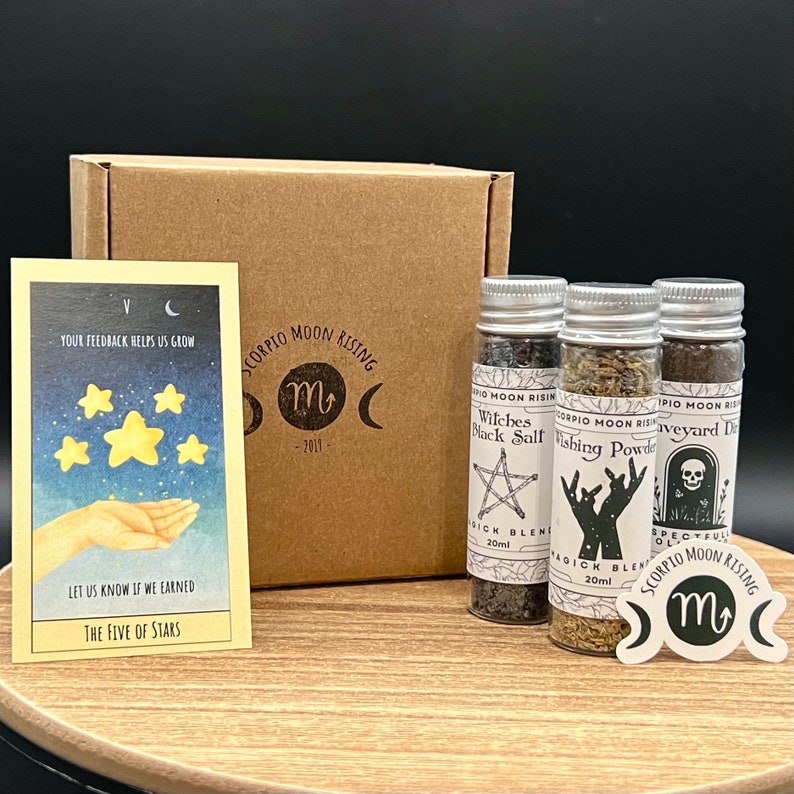 May include: A product display featuring a tarot card, three glass bottles with labels, a cardboard box, and a sticker. The tarot card reads "The Five of Stars." The bottles are labeled "Witches Black Salt," "Wishing Powder," and "Graveyard Dirt."