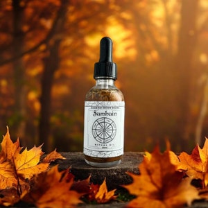 May include: A clear glass bottle with a black dropper lid and a white label. The label says "Scorpio Moon Rising Samhain Ritual Oil 60ml". The bottle is sitting on a wooden surface with autumn leaves around it.