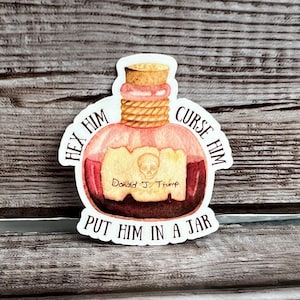 May include: A sticker featuring a potion bottle design with the text "HEX HIM CURSE HIM PUT HIM IN A JAR." The bottle contains a skull and the name "Donald J. Trump."