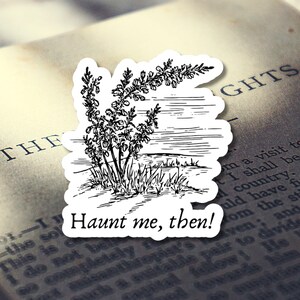 Puede incluir: Una pegatina blanca con una ilustraci&oacute;n en blanco y negro de una planta y un paisaje. La pegatina tiene el texto "Haunt me, then!" en una fuente negra estilizada. La pegatina est&aacute; colocada encima de un libro abierto.