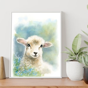 May include: A watercolor painting of a white lamb with blue eyes, looking directly at the viewer. The lamb is surrounded by blue flowers and a soft, green background.