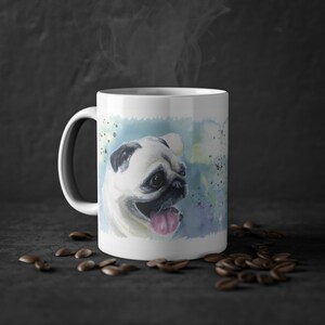 May include: White ceramic mug with a watercolor illustration of a pug dog with a blue, green, and yellow background.