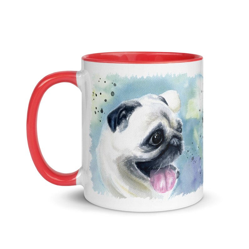 May include: White ceramic mug with a red rim featuring a watercolor painting of a pug dog with a light blue background. The pug is looking to the right and has its tongue sticking out.
