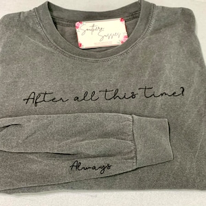 May include: A gray long-sleeve shirt with the phrases "After all this time?" and "Always" embroidered in black. The shirt has a crew neck and a tag that says "Southern Susses" with floral accents.
