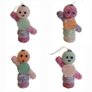 May include: Four colorful, handmade Christmas ornaments shaped like whimsical figures. Each ornament is composed of stacked, textured spheres in various pastel colors, with small black eyes and a smiling face. A gold wire loop is attached for hanging.