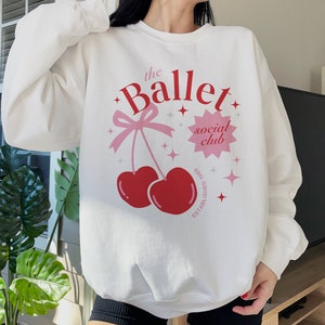 May include: White sweatshirt with a pink and red cherry graphic and the text "the Ballet social club established 1986".