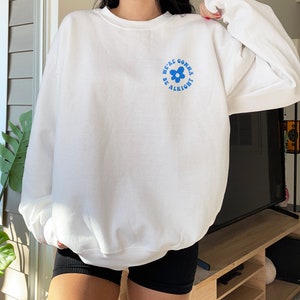 May include: White sweatshirt with a blue flower graphic and the text "We're gonna be alright".