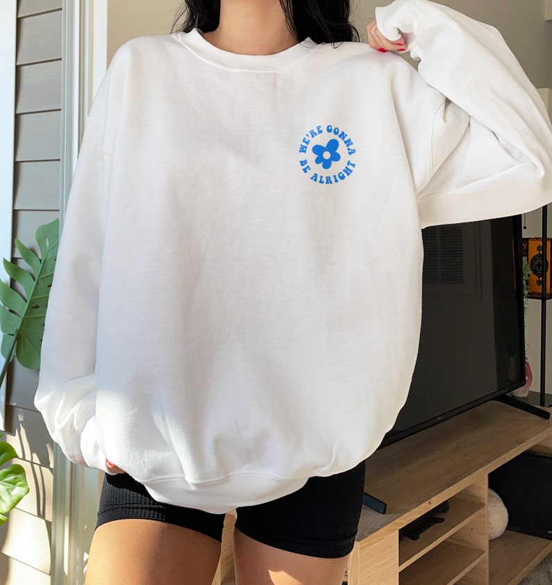 May include: White sweatshirt with a blue flower graphic and the text "We're gonna be alright".