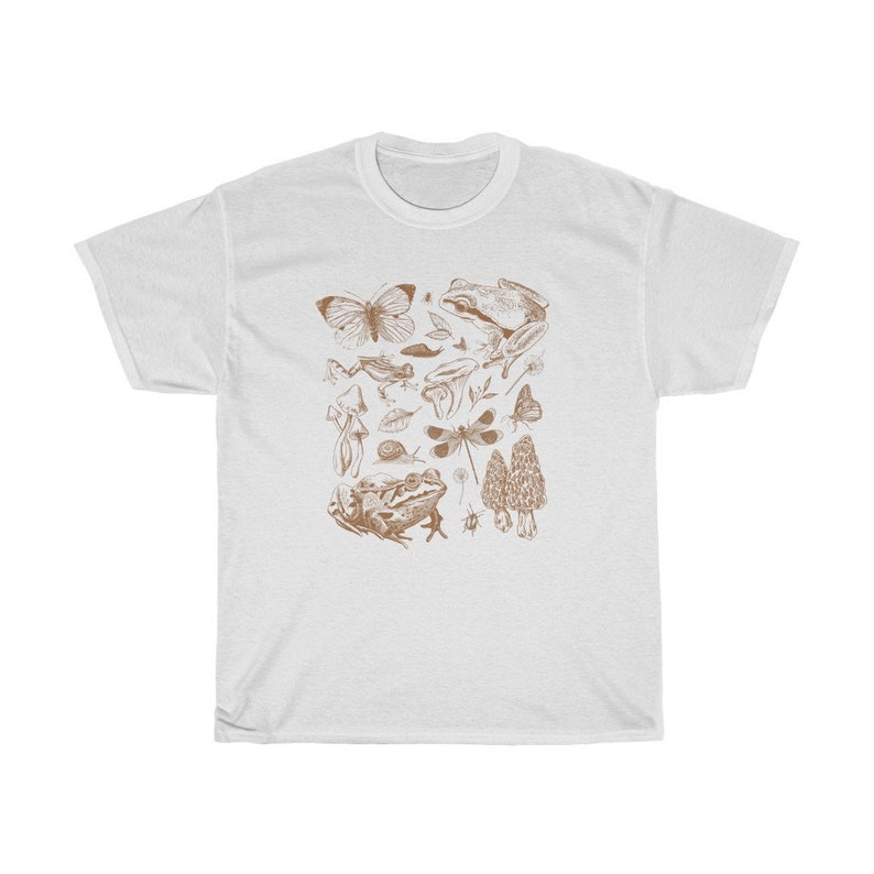 May include: White t-shirt with a brown illustration of various forest creatures, including butterflies, frogs, mushrooms, and a dragonfly.