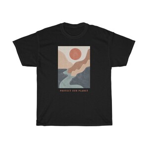 May include: Black t-shirt with a graphic of a stylized landscape with a river, mountains, and a red sun. The text "PROTECT OUR PLANET" is printed below the graphic.