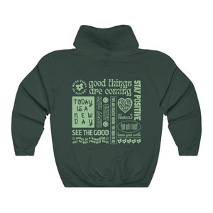 May include: Green hooded sweatshirt with a light green print of motivational phrases and a flower graphic. The text includes "good things are coming", "today is a new day", "happy days ahead", "see the good", "stay positive", "you got this", and "know your worth".