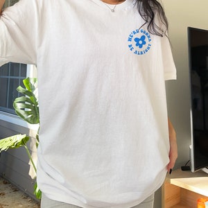May include: White oversized t-shirt with a blue graphic of a flower and the text "We're gonna be alright".