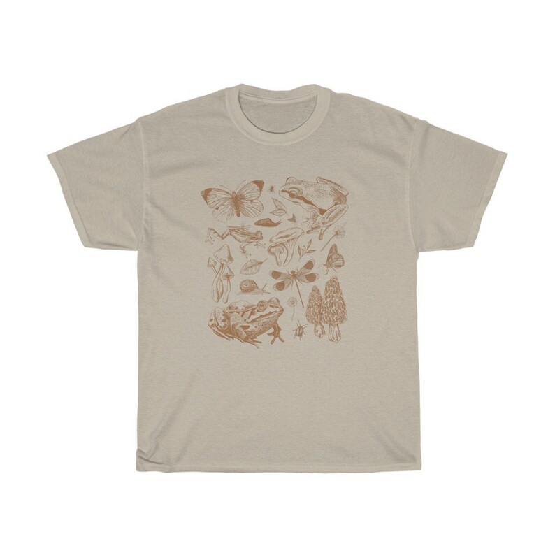 May include: A beige t-shirt with a brown graphic print of various forest creatures, including butterflies, frogs, mushrooms, and dragonflies.