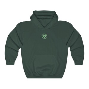 May include: A dark green hooded sweatshirt with a light green flower graphic and the text "We're gonna be alright" in a circle.