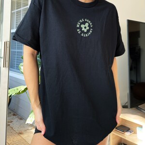 May include: Black t-shirt with a green flower graphic and the text "We're gonna be alright" in a circle.