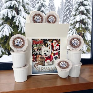May include: A white gift box filled with white coffee pods, each with a logo of a dog. The box features a festive image of a dog in a red sweater with the text "Naughty Holiday Blend" and "Nirvana Coffee Roasters". The background shows snow-covered trees.