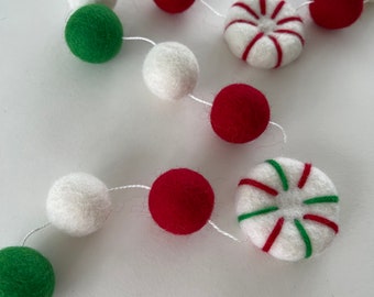 May include: A festive garland with red, white, and green felt balls and peppermint candy ornaments. The garland is perfect for decorating a Christmas tree or mantel.