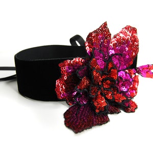 SEQUIN FLOWER CHOKER - Black, wide velvet choker with a 3D flower made of red and pink sequins. The jewelry is tied with satin ribbons.