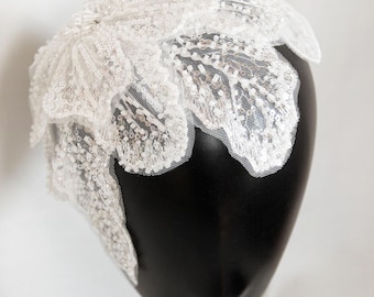 ファイナルタッチホワイト - 花のような白い柔軟なヘッドピース。パールとスパンコールで装飾され、2つの金属製クリップで留める。