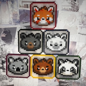 May include: A selection of pixel art animal portraits, including a red panda, koala, bear, and panda bear. Each square design is framed with a contrasting colour, creating a playful and colourful display. The art is made with small, colourful beads.