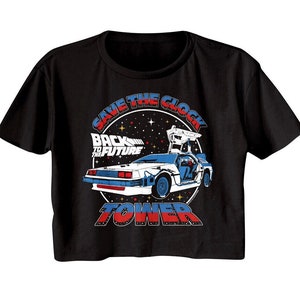 May include: Black crop top t-shirt featuring a graphic of the DeLorean time machine from the movie "Back to the Future." The design includes the text "Save the Clock Tower" in red and blue, with a starry background.