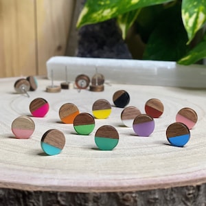 May include: Assortment of 12 colorful wooden earrings. Each earring is a half circle of wood with a contrasting color on the other half. The colors include pink, green, yellow, blue, orange, purple, and black.