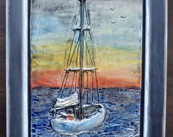 May include: A framed nautical artwork depicting a sailboat on the sea at sunset. The painting features a white sailboat with a mast and sails, set against a backdrop of blue water and a colorful sky. The artwork is framed in a gray wooden frame.