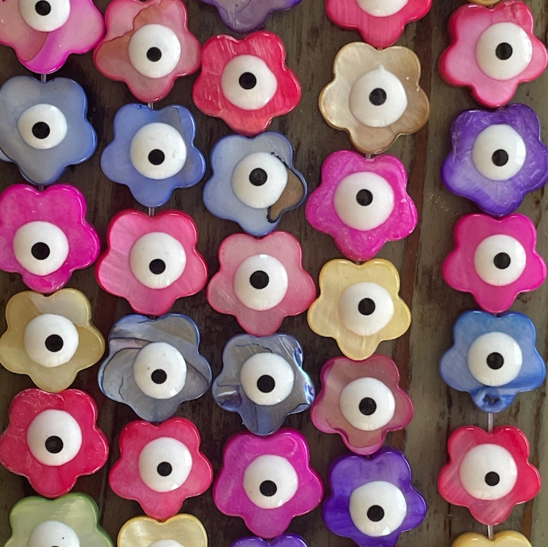 May include: A string of colorful flower-shaped beads with an evil eye charm in the center of each bead. The beads are made of mother of pearl and have a glossy finish.
