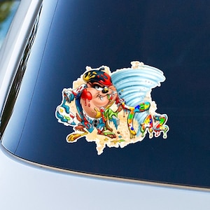 May include: A colorful sticker featuring Taz the Tasmanian Devil in a whirlwind of paint splatters. The sticker has a distressed, torn look and the word "Taz" is visible in the paint.