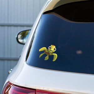 May include: A green sea turtle with a yellow shell and a friendly smile is featured on a car window sticker. The turtle is swimming with its flippers outstretched.