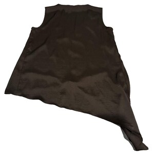 Peut inclure: Un haut sans manches marron fonc&eacute; avec un ourlet asym&eacute;trique. Le tissu a un l&eacute;ger &eacute;clat, sugg&eacute;rant du satin ou de la soie. C'est un v&ecirc;tement &eacute;l&eacute;gant, adapt&eacute; &agrave; diverses occasions.