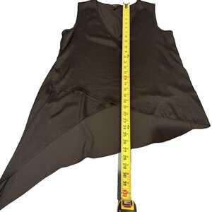 Peut inclure: Un haut sans manches, marron fonc&eacute;, avec un col en V et un ourlet asym&eacute;trique. Un m&egrave;tre ruban jaune s'&eacute;tend du bas, indiquant une longueur d'environ 81 cm.