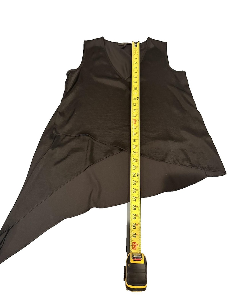 Peut inclure: Un haut sans manches, marron fonc&eacute;, avec un col en V et un ourlet asym&eacute;trique. Un m&egrave;tre ruban jaune s'&eacute;tend du bas, indiquant une longueur d'environ 81 cm.
