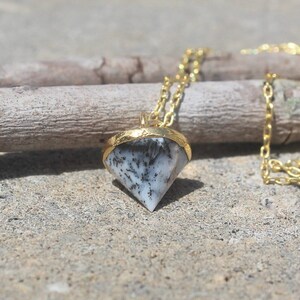 May include: A gold chain necklace with a black and white agate pendant in the shape of a diamond.