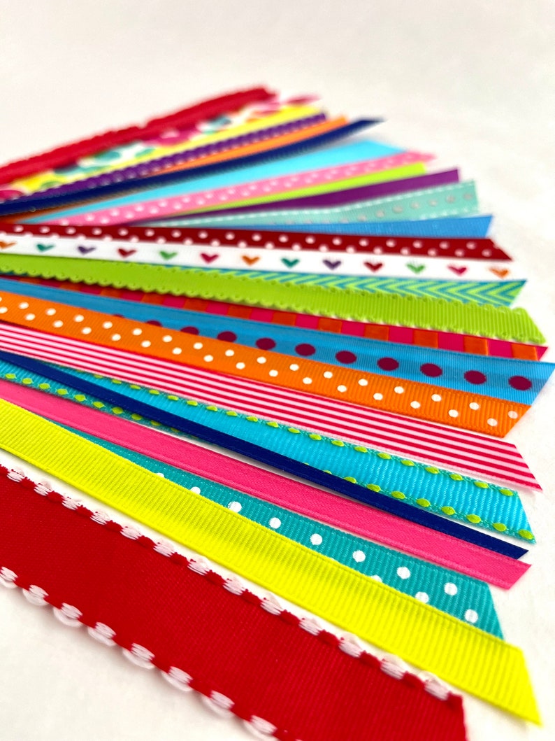 May include: Assortment of colorful ribbon trims with various patterns, including polka dots, stripes, hearts, and zigzags. The ribbons are arranged in a fan shape, showcasing the different designs.