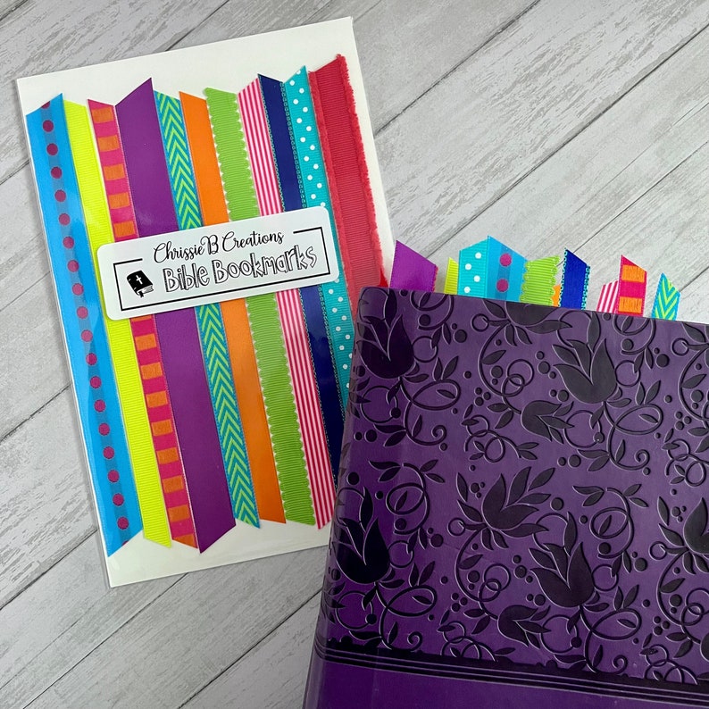 May include: A set of colorful ribbon bookmarks with a white label that reads "Chrissie B Creations Bible Bookmarks".