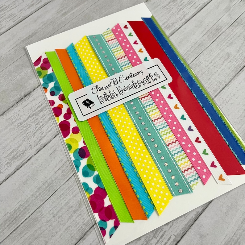 May include: A set of 10 colorful ribbon bookmarks with various patterns, including polka dots, hearts, and waves. The ribbons are packaged on a white card with the text "Chrissie B Creations Bible Bookmarks".